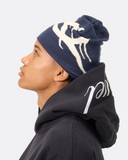 Person wearing a navy beanie with a white logo and a black hoodie with a white logo on a light gray background